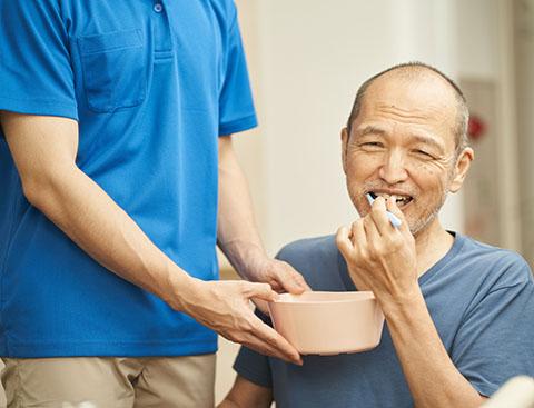 Healthcare provider assisting a stroke survivor with brushing their teeth. 