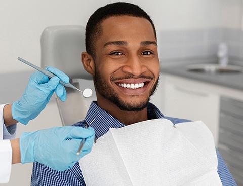 A man seated in a dentist’s chair, smiling.